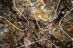 Nærbilde av stein med mineral i. Grafisk hvit dubinform oppå.