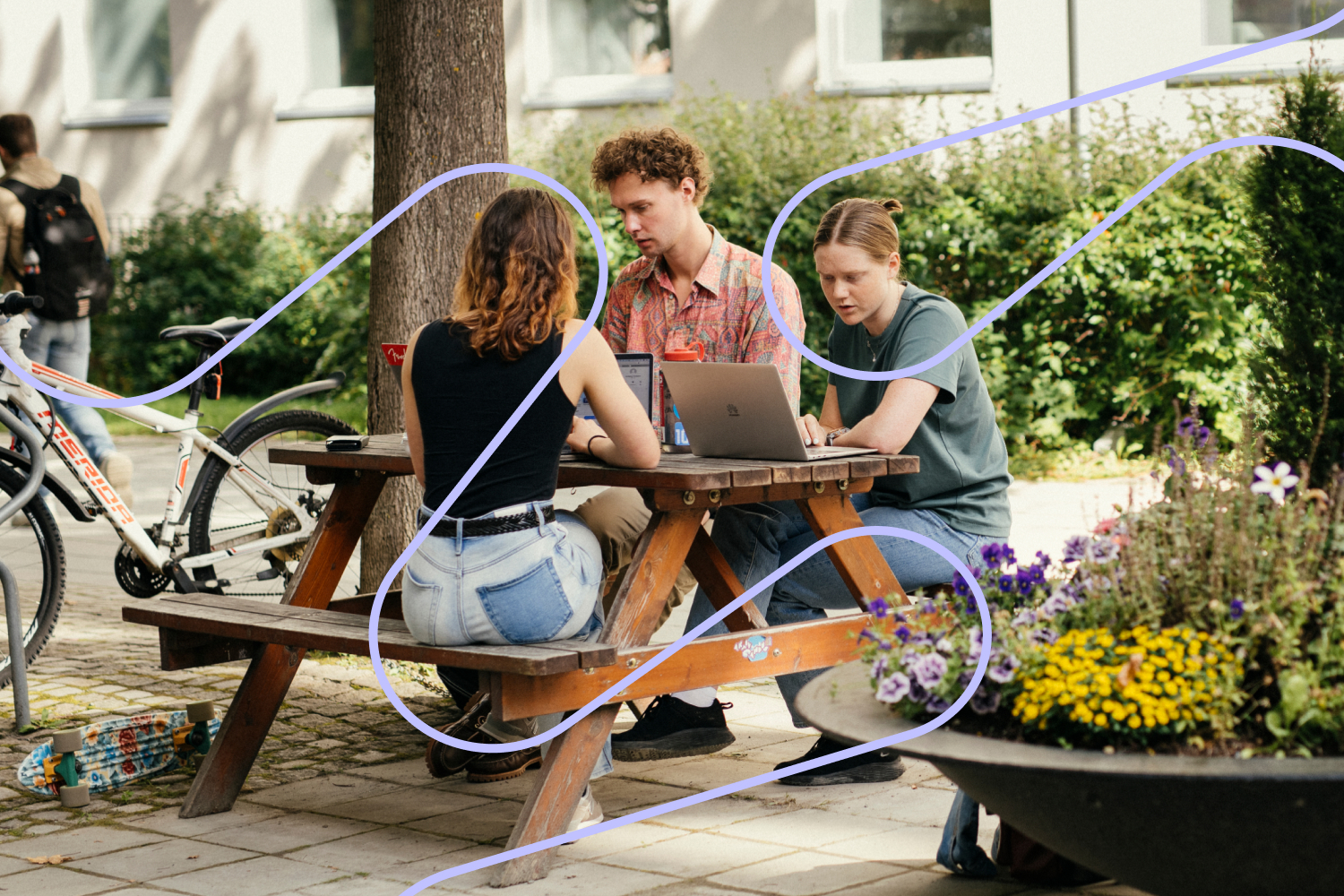 to kvinnlige og en mannlig student sitter med hver sin PC ved et picnicbord