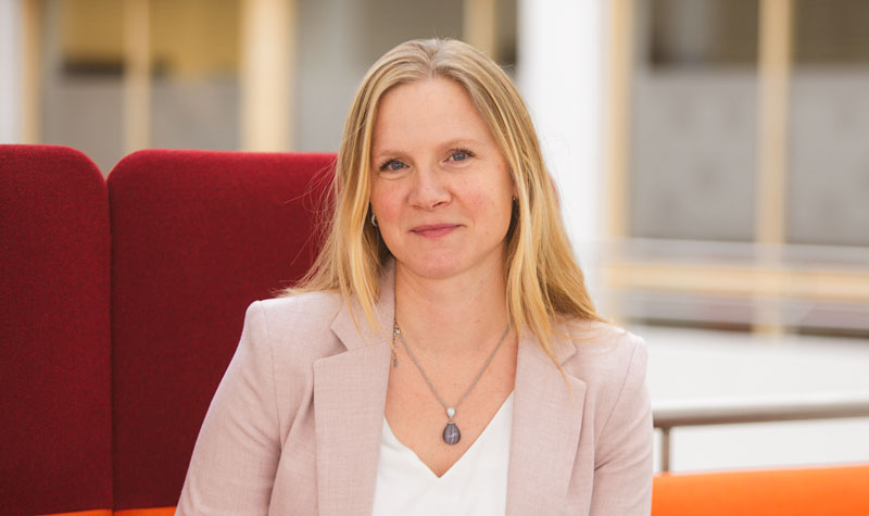 Portrett av Mari Sundli Tveit i en rød sofa